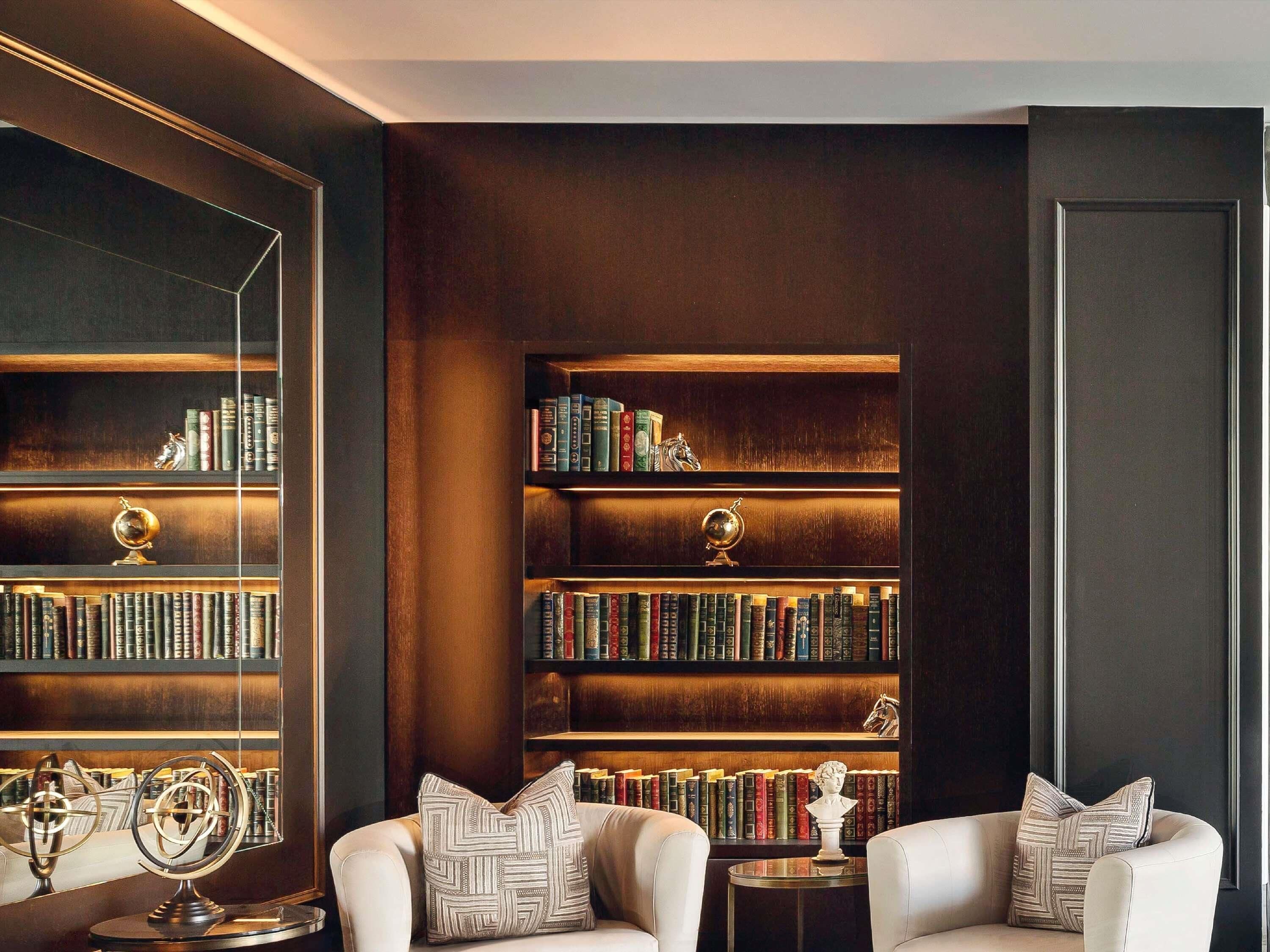 A library with bookshelves, leather armchairs, and a globe.
