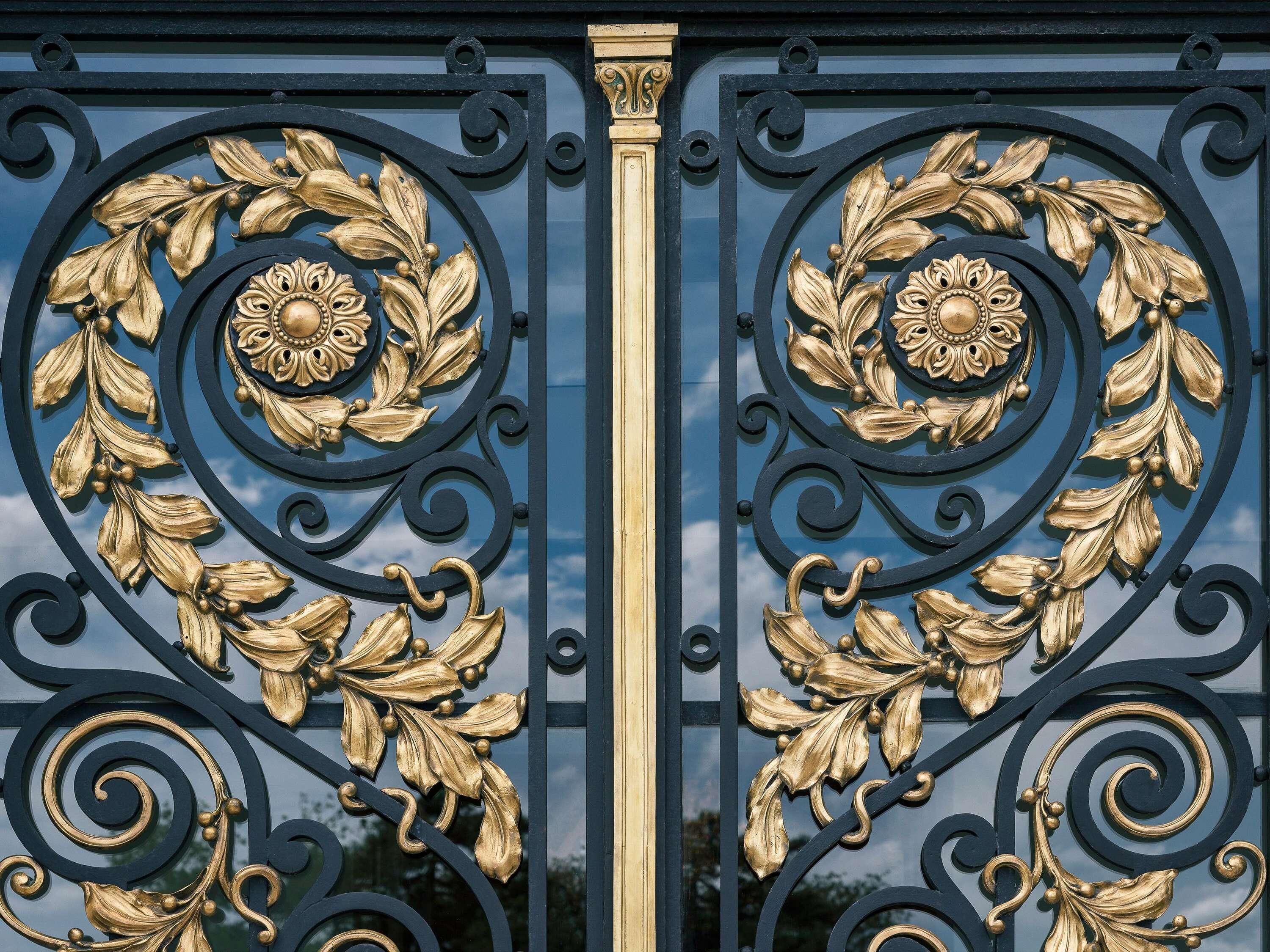 Um portão de ferro forjado preto com desenhos florais e em espiral detalhados.
