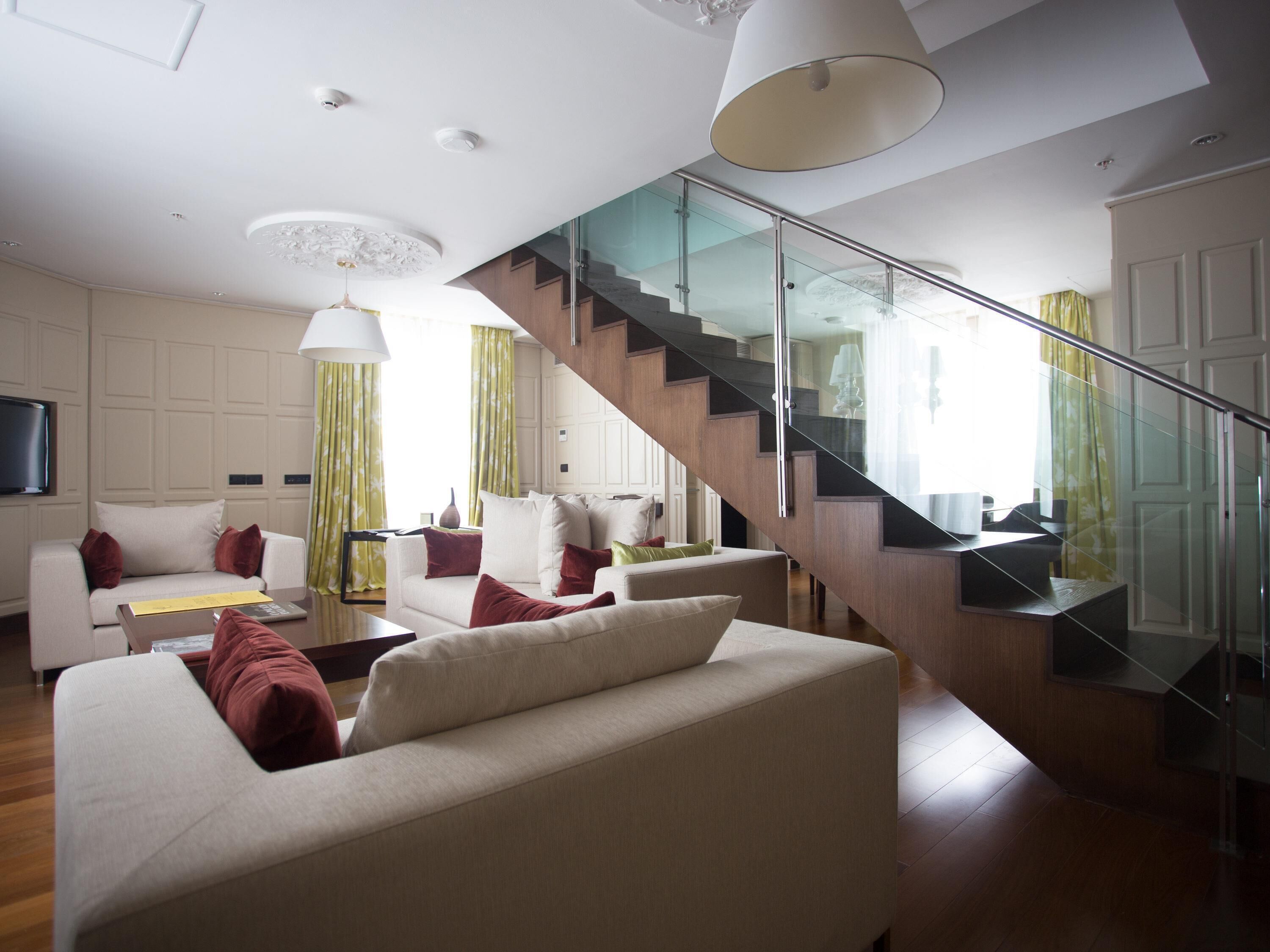 Ein modernes Wohnzimmer mit Treppe, Sofas und einem Flachbildfernseher.