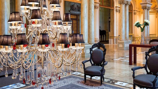 Un vaste hall d’entrée agrémenté d’un grand lustre, de colonnes richement décorées et de meubles classiques.