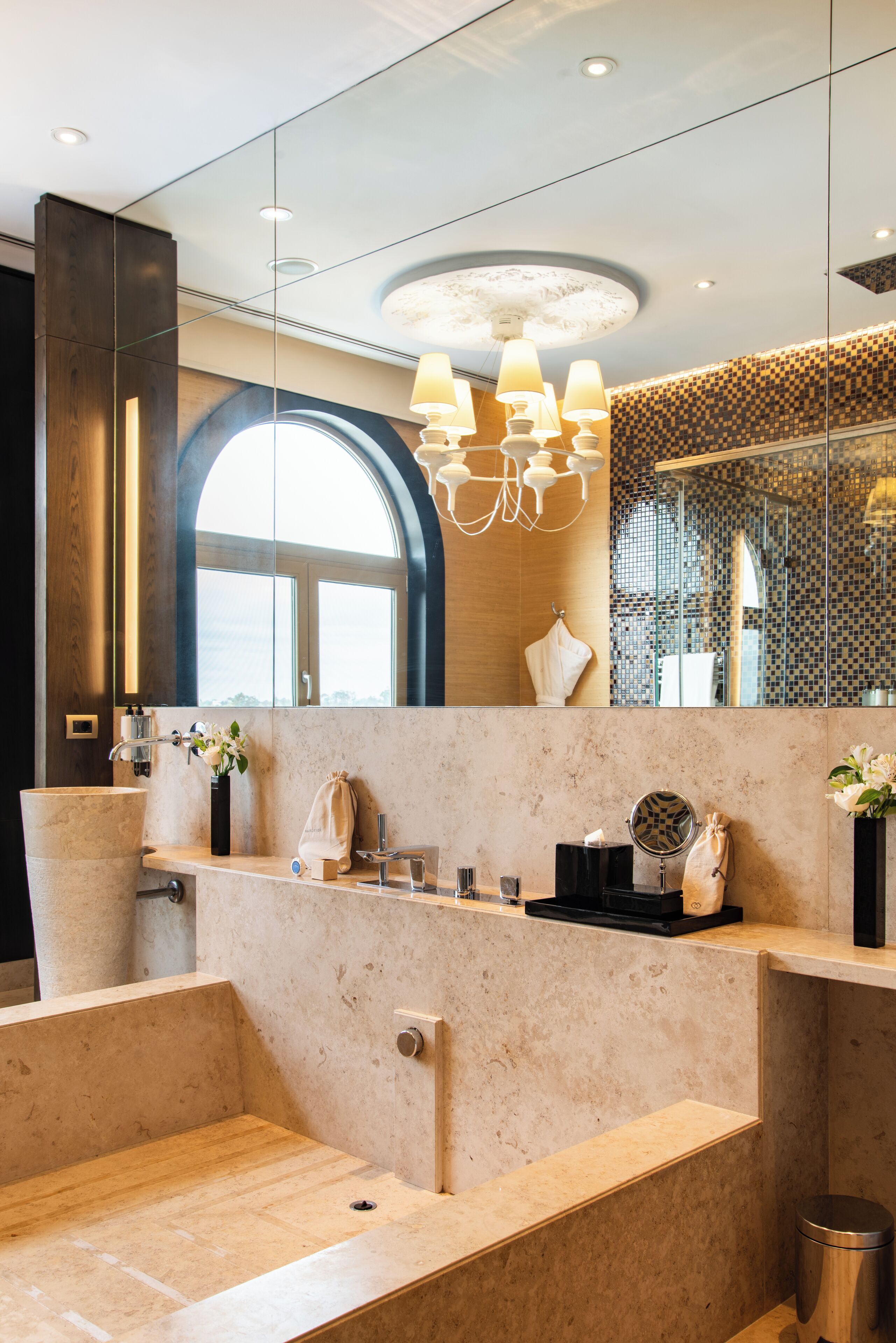 A modern bathroom with a large mirror, a sink, a vanity, and a shower area.