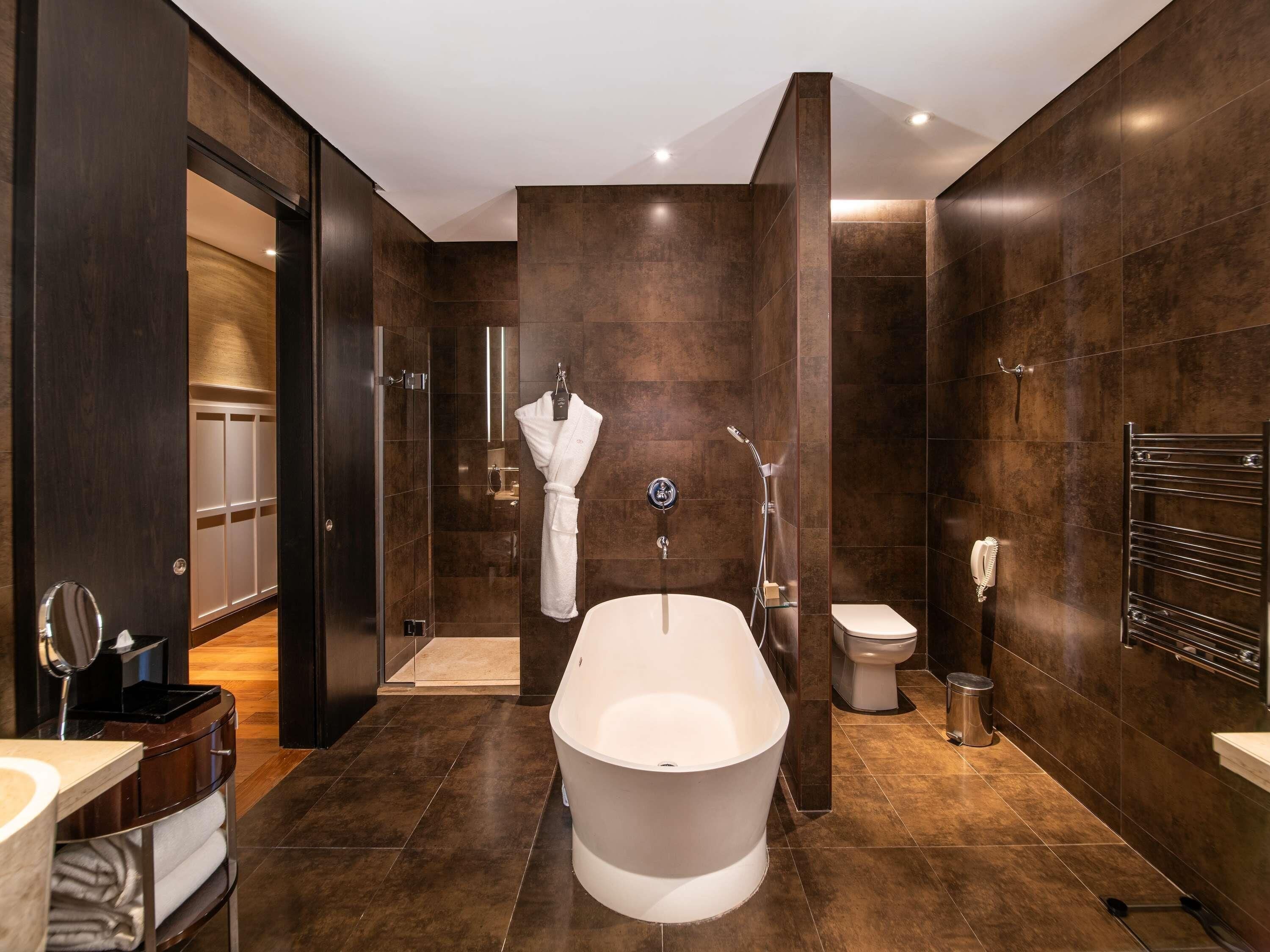 Un baño moderno con una bañera independiente, inodoro y zona de ducha.