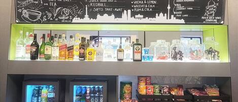 A bar area with a chalkboard menu listing drinks and a selection of bottles and glasses.