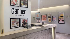Ein Hotel-Empfangsbereich mit gerahmten Kunstwerken an den Wänden, einem Empfangstresen und einem klaren, modernen Design.