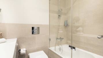 Un baño moderno con ducha de vidrio, inodoro blanco y bañera.