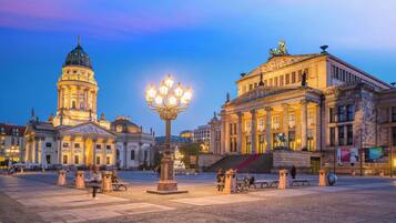 A historic building with a dome and classical architecture, a public square with a fountain, and a statue on a pedestal.