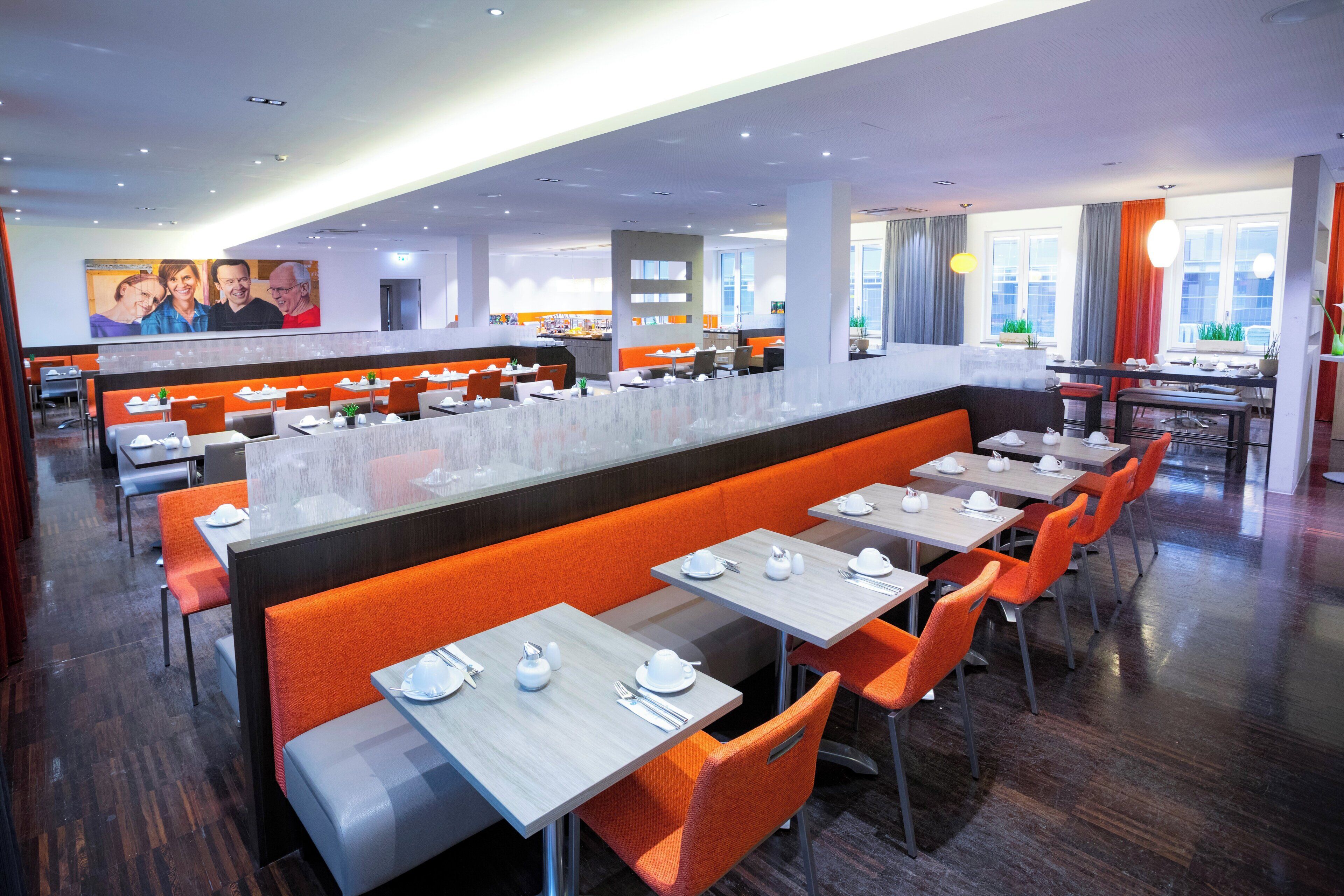 A modern restaurant with booths and tables, a bar area, and a view of the city.
