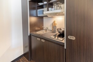 Una cucina compatta con forno a microonde, lavello e piano cottura integrato.