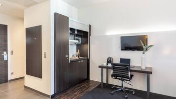 Un espace de bureau moderne comprenant un bureau, une chaise et un téléviseur à écran plat fixé au mur.