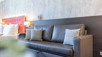 Habitación de hotel moderna con sofá de cuero gris, cabecera roja y pared de hormigón.