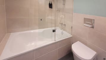 A modern bathroom with a glass-enclosed shower, a white bathtub, and a toilet.