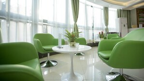A modern hotel lobby with green chairs, a white round table, and large windows with sheer curtains. - Vatica Hefei Huizhou Avenue Chinese Academy Of Soc (Hefei)