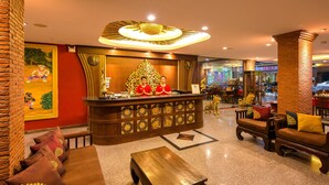 A lobby with a reception desk, seating area, and decorative elements. - Tanawan Phuket Hotel (Patong)