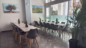 A conference room with a long table, chairs, potted plants, and artwork on the walls. - Paloma (Athens)