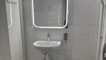 A small bathroom with a white sink, a mirror, and a toilet.