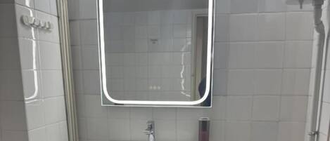 A small bathroom with a white sink, a mirror, and a toilet.