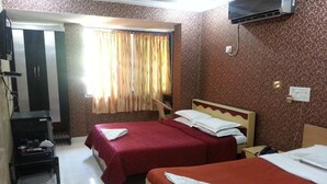 Une chambre d’hôtel avec deux lits, une télévision et un bureau avec une chaise.