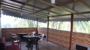 Un espace extérieur abrité, doté d’un mur en briques, d’un plancher en bois et d’un ventilateur de plafond.