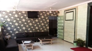 Un salon comprenant un canapé, deux tables basses, un téléviseur et une porte-fenêtre coulissante.