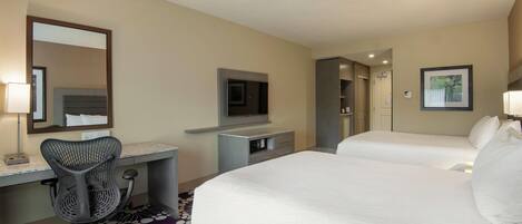 A hotel room with a bed, a desk with a chair, a television, and a mirror.