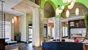 Eine moderne Lobby mit einer Sitzecke, einem Kamin und einer großen Pflanze.