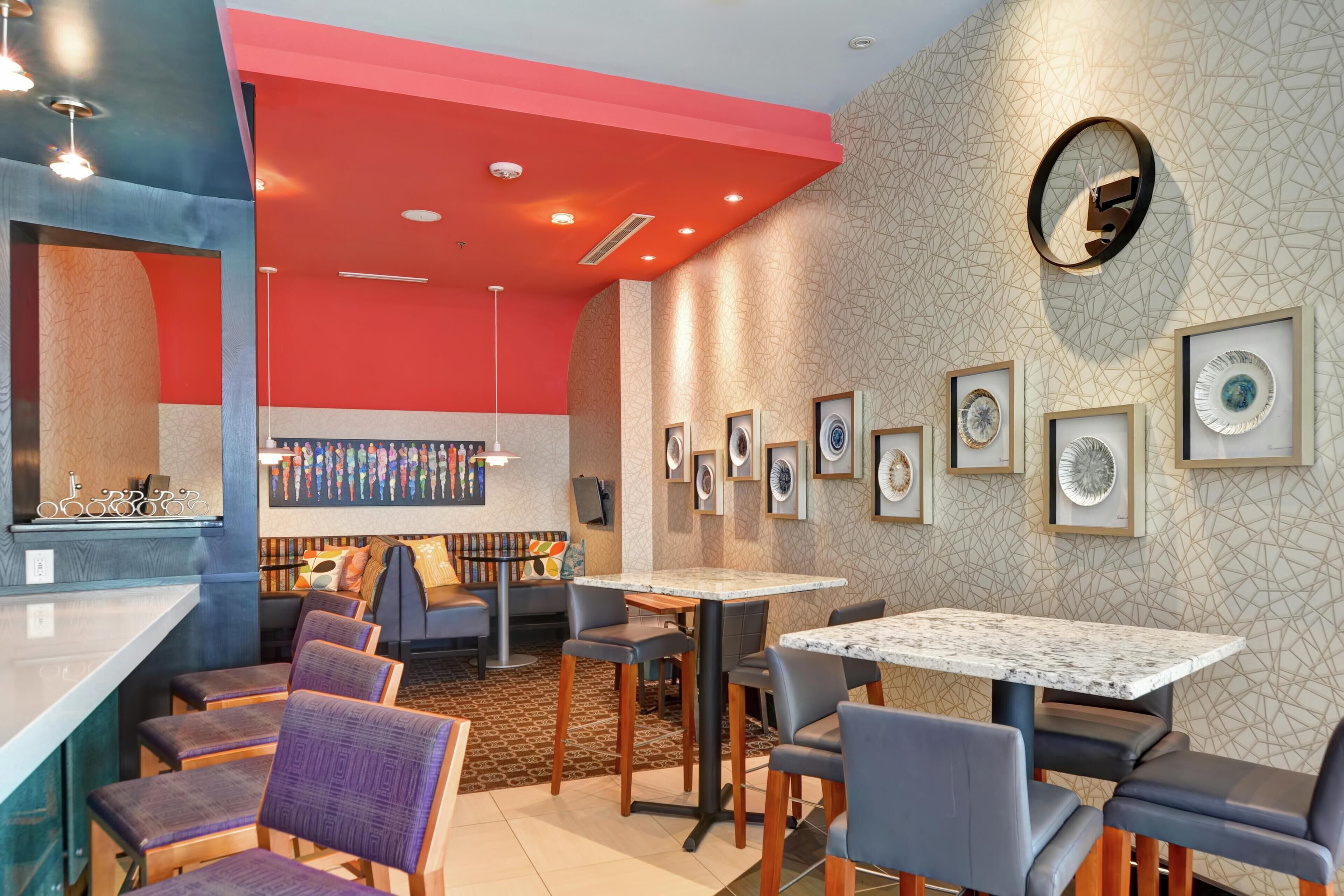 A restaurant with a bar area, seating with cushioned chairs, and framed artwork on the walls.