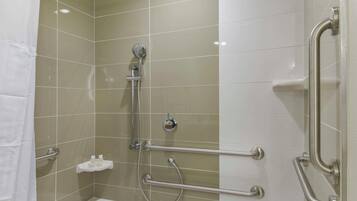 A bathroom with a shower, grab bars, and a white bathtub.