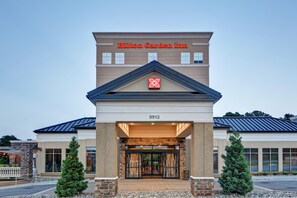 A Hilton Garden Inn with a modern facade, a prominent logo, and a numbered address.