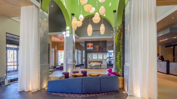 Eine moderne Lobby mit einem grünen Bogen, einer Sitzecke und einem Empfangstresen.