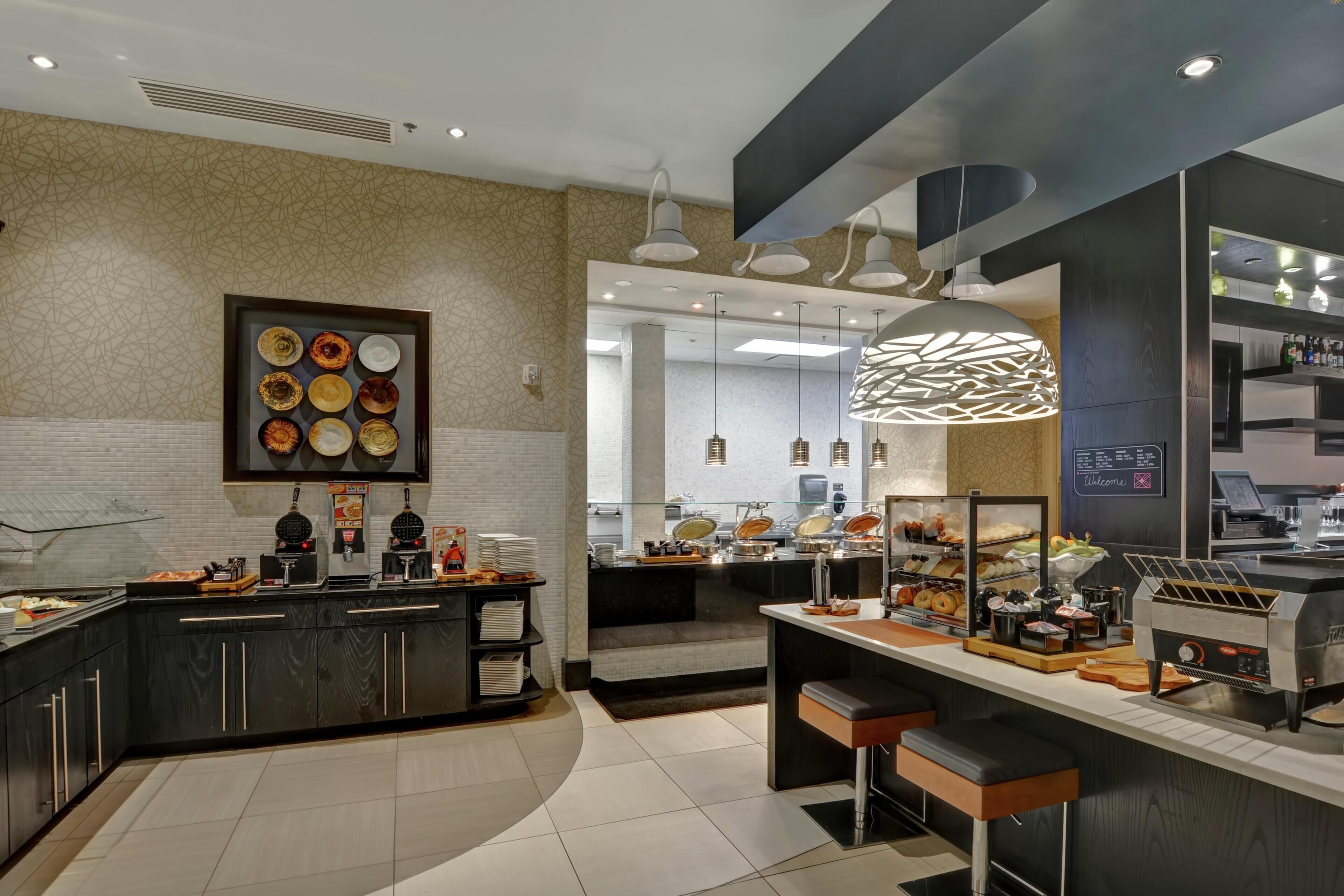 A modern kitchen with a buffet setup, including a variety of food items and a coffee station.