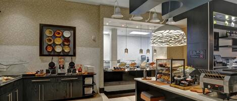A modern kitchen with a buffet setup, including a variety of food items and a coffee station.