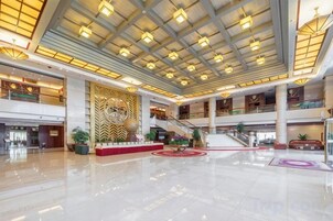 A spacious lobby with a high ceiling, multiple floors, and a central staircase.