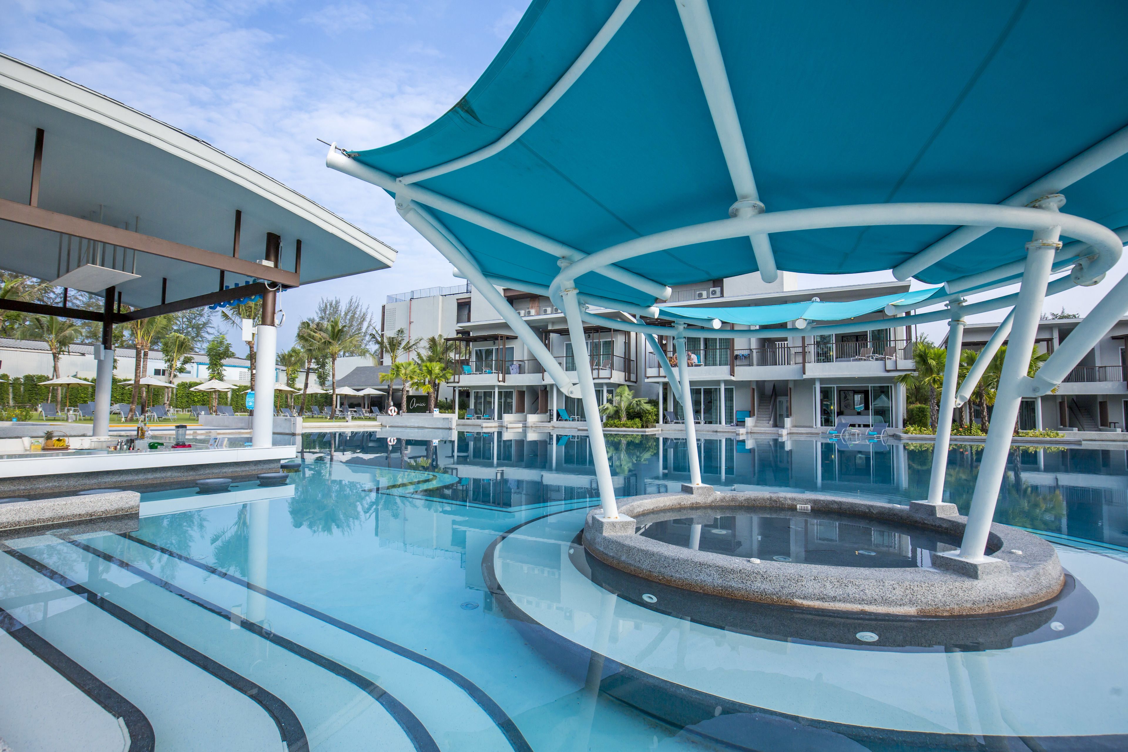 A modern pool area with a circular water feature, lounge chairs, and a covered seating area.