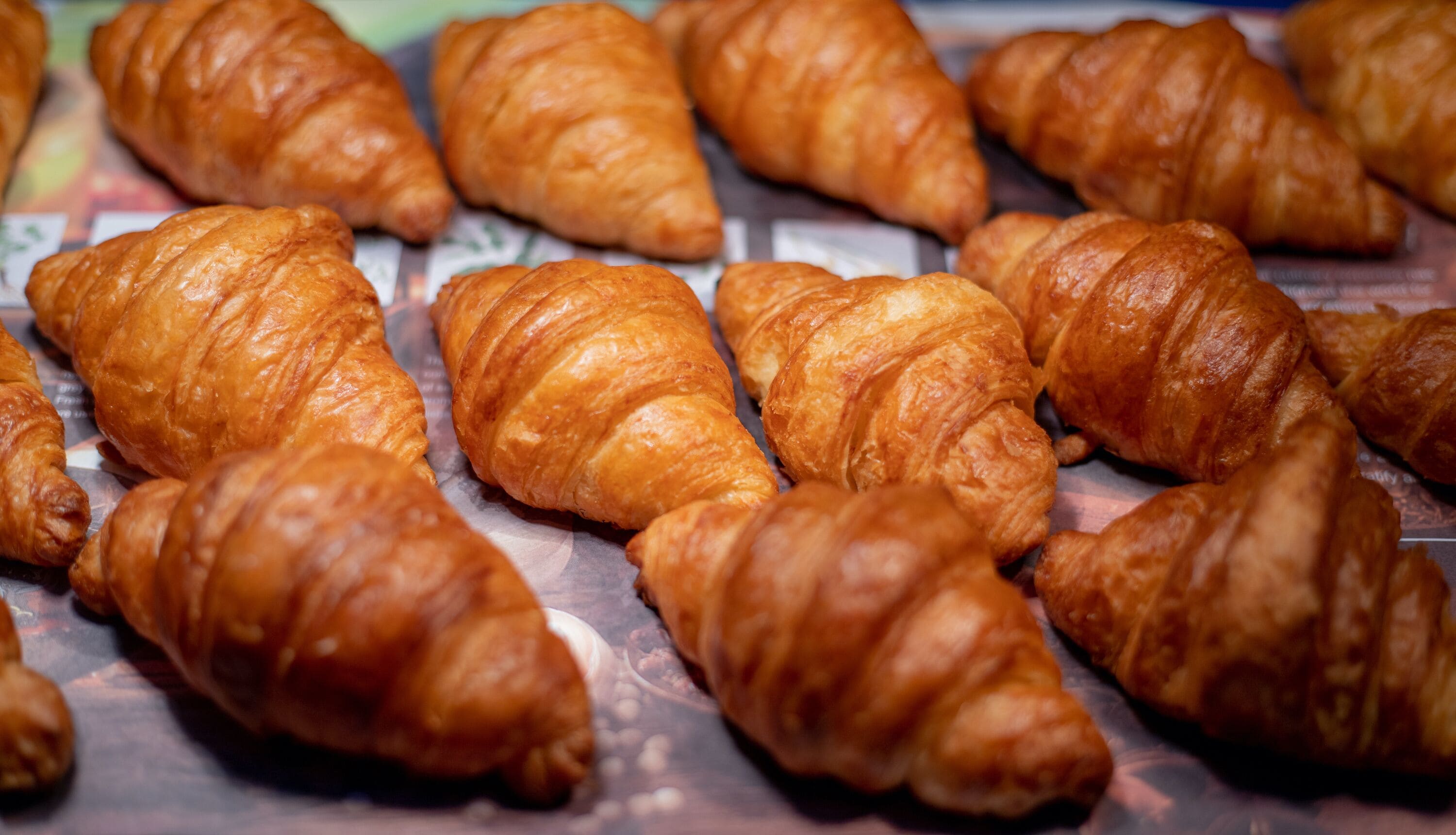 A display of golden-brown croissants arranged on a tray.
