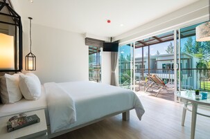 Una habitación de hotel moderna con una cama grande, televisor y balcón con una silla y una mesa.