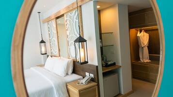 A hotel room with a bed, bedside table, lamp, and a mirror.