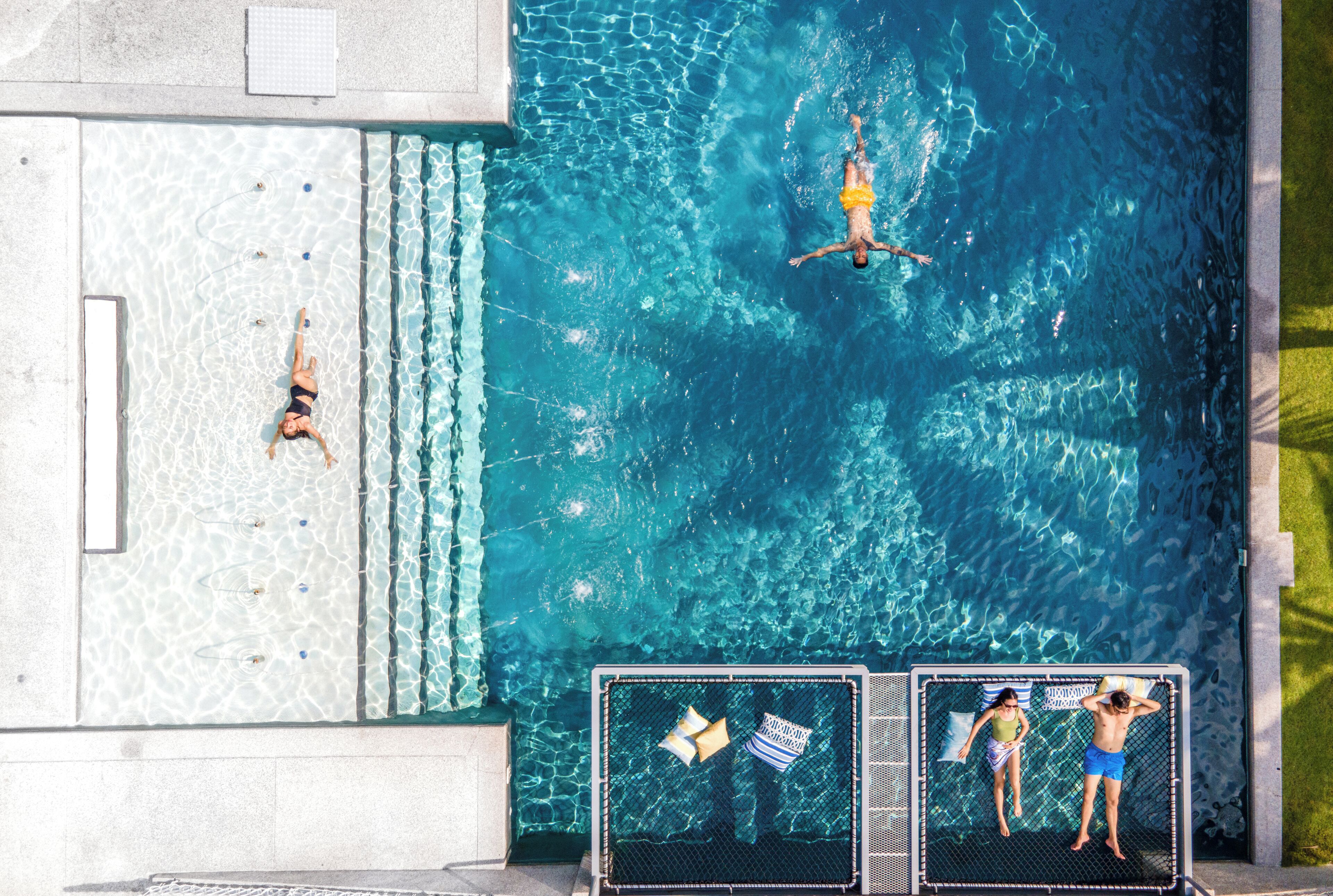 A swimming pool with clear blue water, a diving board, and a lounge chair.