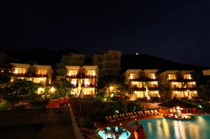 Una piscina al aire libre, sombrillas, sillones reclinables de piscina