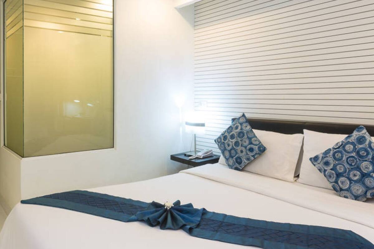 A hotel room with a large bed, a bedside table with a lamp, and a wardrobe.