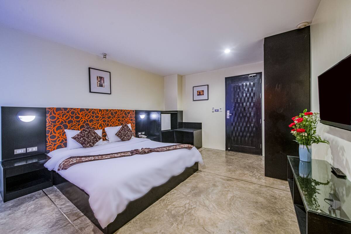 A hotel room with a large bed, a nightstand, a desk, and a door.