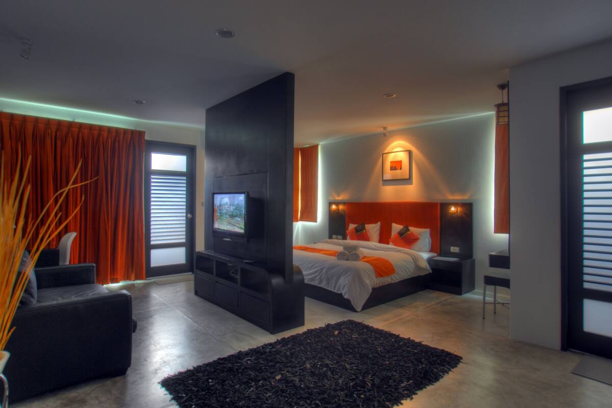 A modern bedroom with a large bed, a TV, and a black entertainment unit.