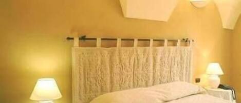 A bedroom with a bed, two bedside lamps, a headboard, and a wall with a textured design.