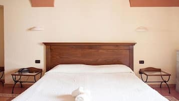 Un lit bien fait, avec une tête de lit en bois, deux tables de chevet et un luminaire fixé au mur.