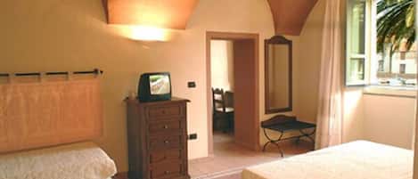 Une chambre avec deux lits, une commode, un téléviseur et une fenêtre avec des rideaux.