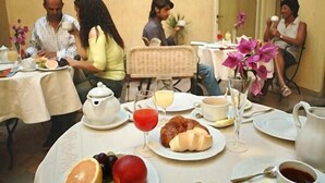 Een ontbijtruimte met gedekte tafels, inclusief borden met croissants, fruit en drankjes.