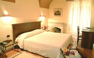 Un dormitorio ordenado con una cama grande, una mesita de noche y una pequeña mesa con un florero.