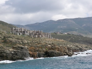 A coastal building with multiple levels and a rugged landscape.