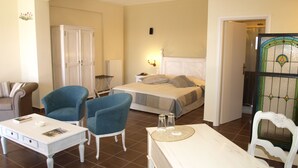 A hotel room with a bed, two armchairs, a small table, and a desk.