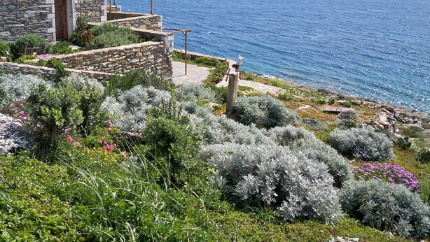 A stone building with a garden and a view of the sea.