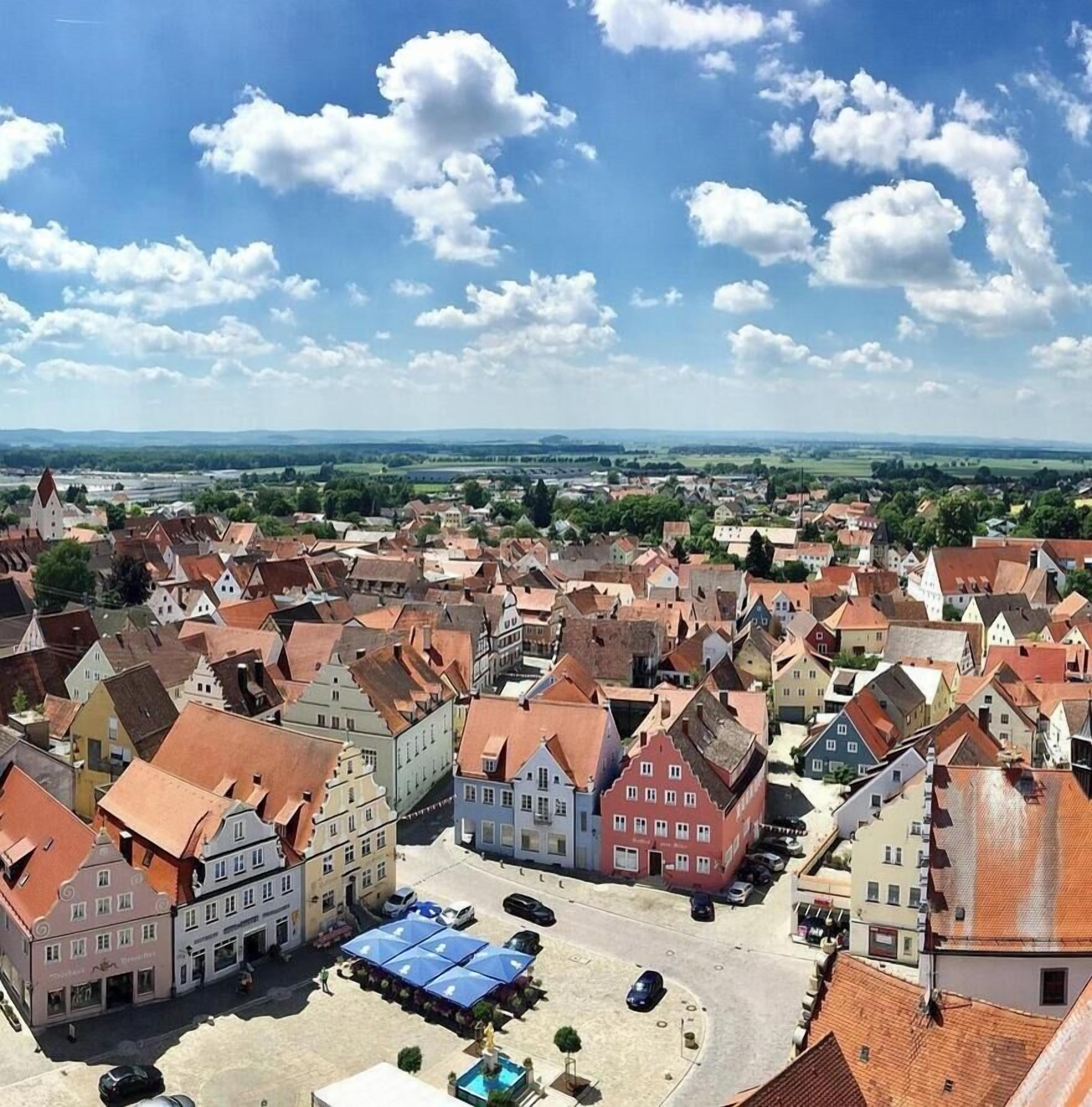 Un pueblo con edificios históricos, una plaza central y una vista distante del campo.